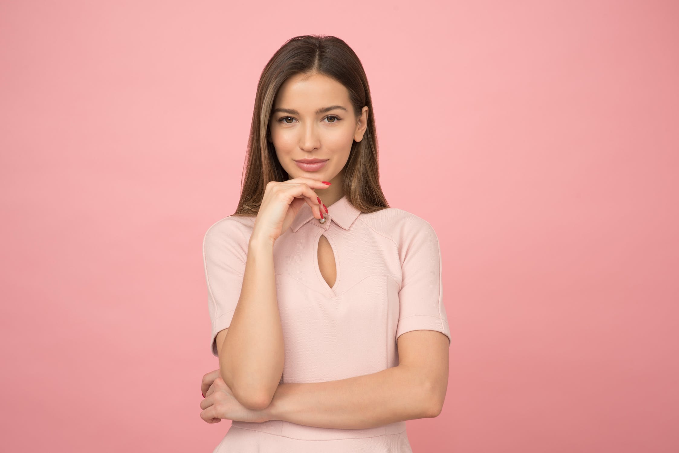 A woman in a pale pink top, smiling to camera